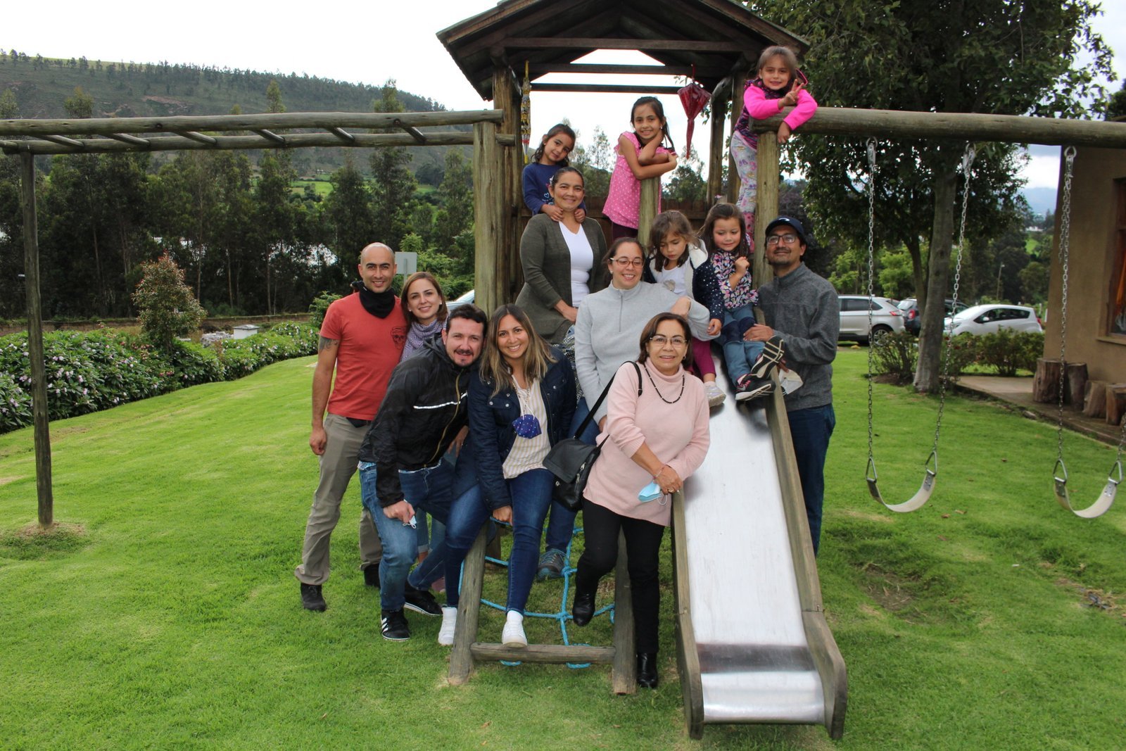 Familia con niños en el parque infantil de madera de La Doña Hacienda, rodeado de césped y árboles