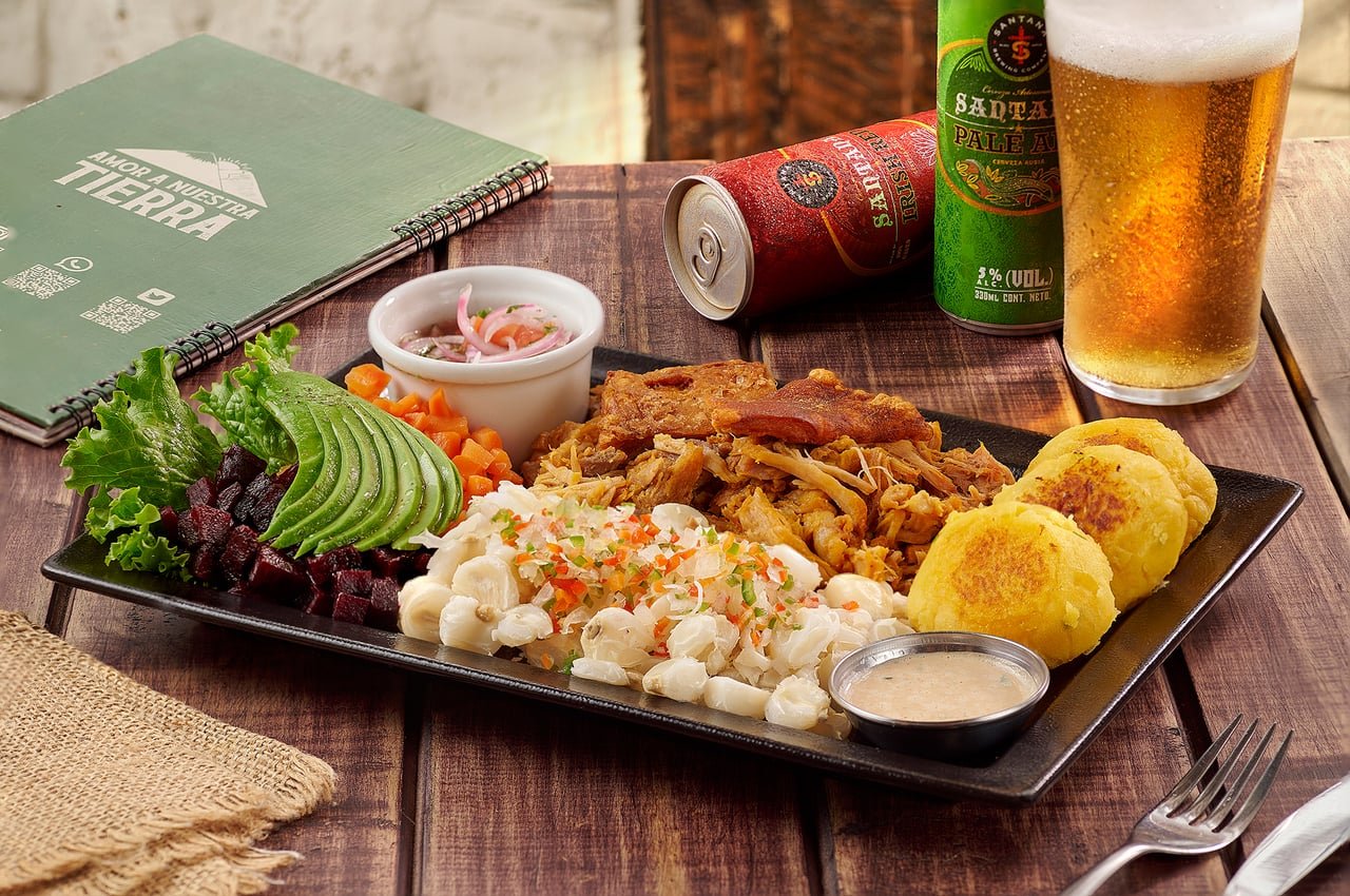 Fritada con llapingachos, mote, curtido, aguacate y remolacha, acompañada de cerveza, en La Doña Hacienda