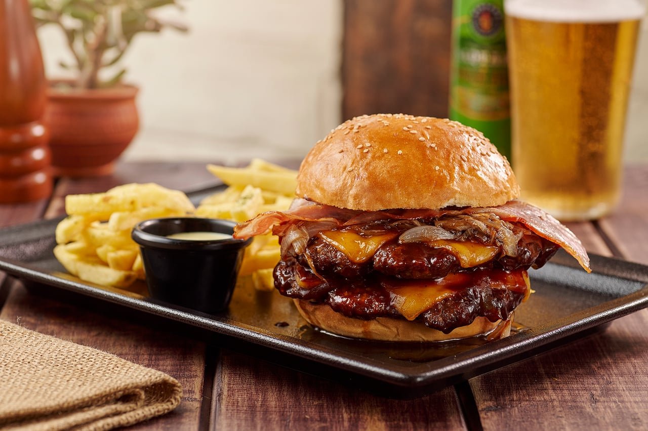 Hamburguesa doble de carne con tocino, queso y papas fritas de La Doña Hacienda