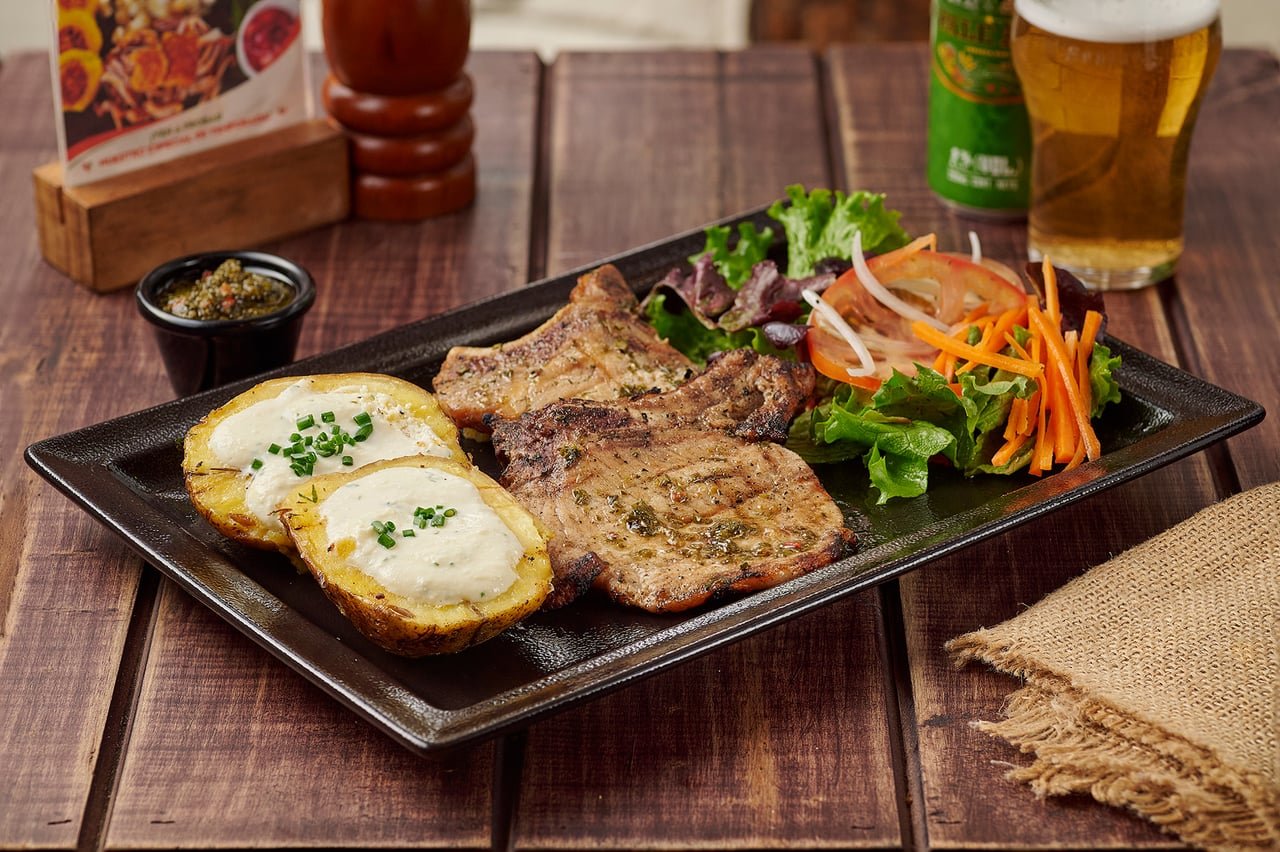 Chuletas de cerdo a la parrilla con papas al horno gratinadas y ensalada fresca en La Doña Hacienda