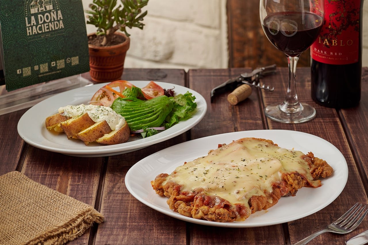 Milanesa apanada gratinada con papa al horno y ensalada de La Doña Hacienda